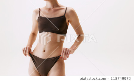 Cropped image of slim female body, fit belly. Model posing in cotton underwear isolated on white studio background 118749973