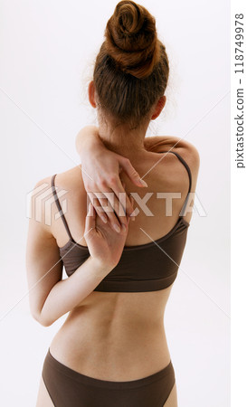 Back pain reduction, massage, stretching. Rear view of woman in underwear demonstrating her healthy back isolated on white studio background 118749978
