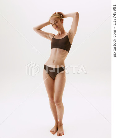 Full-length portrait of beautiful young woman in comfortable cotton underwear posing, showing her healthy slim body isolated on white studio background 118749981