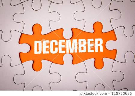 DECEMBER. White puzzle pieces and text on an orange background DECEMBER. White puzzle pieces and text on an orange background 118750656