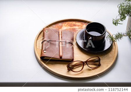 Cozy workspace with notebook, glasses and coffee cup on wooden tray. Cozy workspace with notebook, glasses and coffee cup on wooden tray. 118752144