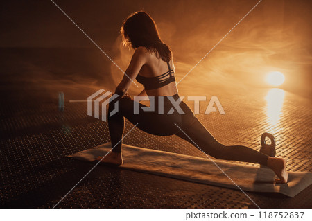 An Elegant Woman Engaged in a Yoga Session Under Dramatic Lighting A Source of Inspiration for Fitness and Wellness Enthusiasts, Showcasing Balance, Calmness, and Concentration in Movement An Elegant Woman Engaged in a Yoga Session Under Dramatic Lighting A Source of Inspiration for Fitness and Wellness Enthusiasts, Showcasing Balance, Calmness, and Concentration in Movement 118752837
