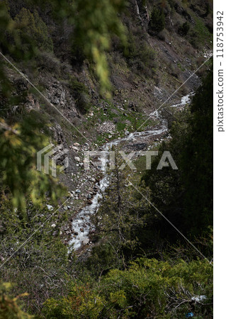 serene, untouched wilderness, winding stream cuts through rugged, mountainous landscape 118753942