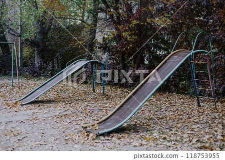 Two old unsafe metal multi-colored children's slides in the Soviet Courtyard. Playground in Bishkek, Kyrgyzstan Two old unsafe metal multi-colored children's slides in the Soviet Courtyard. Playground in Bishkek, Kyrgyzstan 118753955