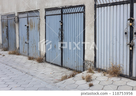 Entrances to parking spaces for cars in the courtyard of an apartment building. Lots of metal garage doors. Garage cooperative. 118753956