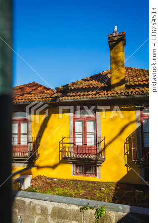a yellow house with a metal hedge and a seagull on the chimney a yellow house with a metal hedge and a seagull on the chimney 118754513