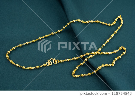 A Gold Necklace on green textile background. 118754843
