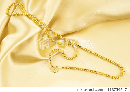Gold Necklace on gold color silk background. Gold Necklace on gold color silk background. 118754847