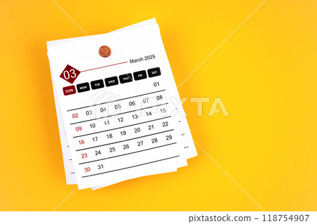 March 2025 calendar page with wooden push pin on yellow background. 118754907