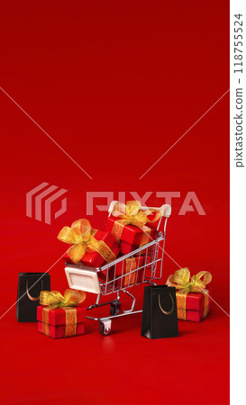 Supermarket trolley with red box with gold bows and black shopping bags. The concept of buying gifts for holidays and sales. Discounts, Black Friday. Red background, Copy space vertical banner Supermarket trolley with red box with gold bows and black shopping bags. The concept of buying gifts for holidays and sales. Discounts, Black Friday. Red background, Copy space vertical banner 118755524