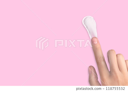 A woman's hand smears white cream. Swatch of white moisturizer. Cream texture, copy space pink background 118755532