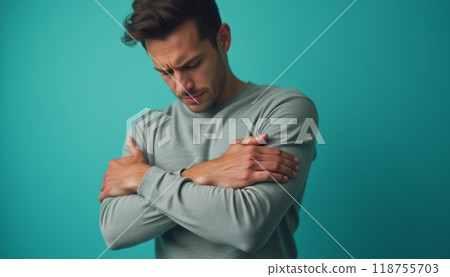 A man in a light gray sweater holds his arm in pain, expressing discomfort and unease. 118755703