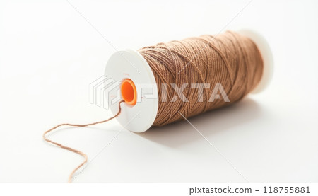 A close-up of a spool of brown thread placed on a white background, representing crafting, sewing, or DIY projects. The simplicity highlights the importance of everyday materials. 118755881