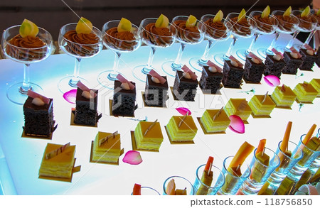 Beautiful multicolored decorated baked sweet tasty party cakes or catering cakes for party, bar dessert selection with cake, pie and pastries catering banquet, coffee break buffet at a conference Beautiful multicolored decorated baked sweet tasty party cakes or catering cakes for party, bar dessert selection with cake, pie and pastries catering banquet, coffee break buffet at a conference 118756850