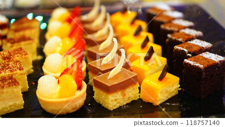 Beautiful multicolored decorated baked sweet tasty party cakes or catering cakes for party, bar dessert selection with cake, pie and pastries catering banquet, coffee break buffet at a conference Beautiful multicolored decorated baked sweet tasty party cakes or catering cakes for party, bar dessert selection with cake, pie and pastries catering banquet, coffee break buffet at a conference 118757140