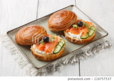 Rich sandwich filled with salmon fillet, cream cheese, fresh cucumber and olives close-up on plate. Horizontal 118757537