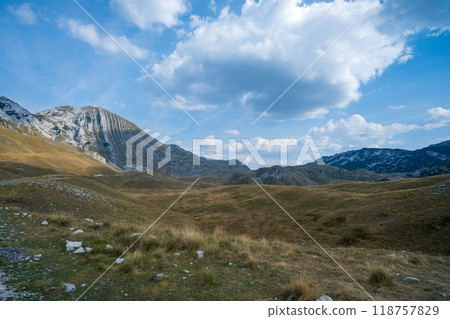 Grassy valley with rocky mountain under blue sky. Durmitor National Park. Montenegro Grassy valley with rocky mountain under blue sky. Durmitor National Park. Montenegro 118757829