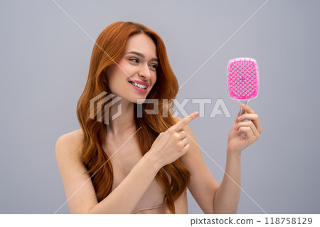 Ginger young woman holding a pink hairbrush in hands 118758129