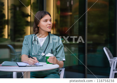Young pretty female doctor making notes and looking involved Young pretty female doctor making notes and looking involved 118758238