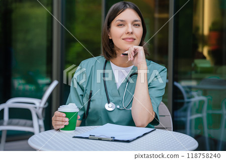 Young female doctor having a coffee break and looking relaxed Young female doctor having a coffee break and looking relaxed 118758240