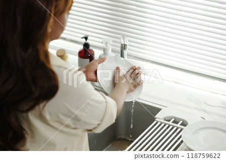 Washing Dishes at Kitchen Sink in Contemporary Environment 118759622