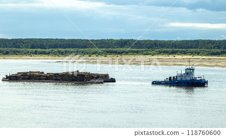 A large river vessel pulls two barges loaded with timber down the river A large river vessel pulls two barges loaded with timber down the river 118760600