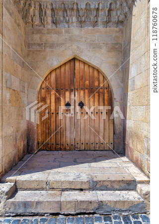 Ancient wooden door with intricate carvings at a historical site in a sunny town square, showcasing rustic charm Ancient wooden door with intricate carvings at a historical site in a sunny town square, showcasing rustic charm 118760678