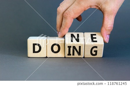 Doing and done symbol. Concept words Doing Done on wooden block. Beautiful grey table grey background. Businessman hand. Business doing and done concept. Copy space. 118761245