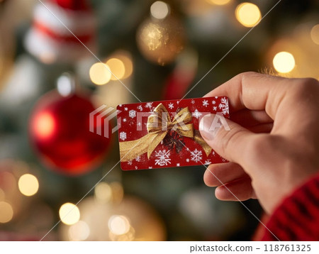 Hand Holding a Red Christmas Gift Card with Gold Bow 118761325