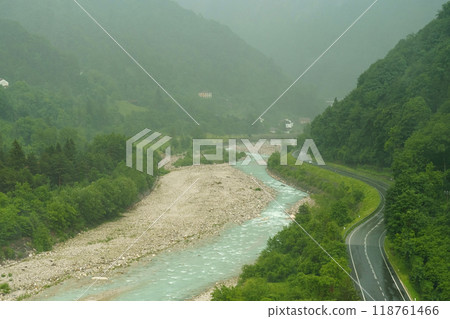 A serene river winding through lush green hills on a misty day captures the tranquil beauty of natures landscape 118761466