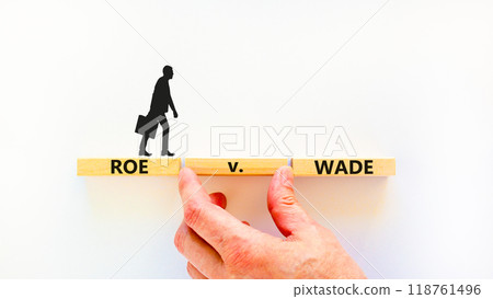 Abortion process Roe versus Wade symbol. Concept words Roe versus Wade on wooden blocks. Lawyer hand. Beautiful white table white background. Abortion process Roe versus Wade concept. Copy space. 118761496
