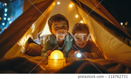 Two smiling children, boy and girl, enjoy a magical moment inside a warm, glowing tent with fairy lights, embodying childhood wonder and imagination 118762731