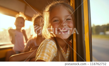 Close up of a beaming young girl with golden hair, leaning out of a school bus window, capturing the excitement and happiness of childhood adventures 118762732