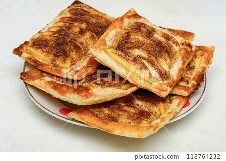 Close-up of apple pastries on a plate with a white background. Close-up of apple pastries on a plate with a white background. 118764232