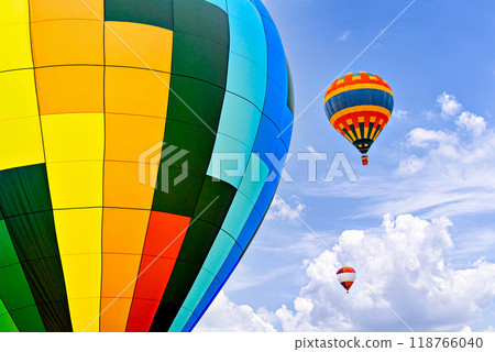 Colorful hot air balloon flying over blue sky with white clouds Colorful hot air balloon flying over blue sky with white clouds 118766040