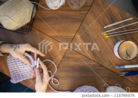 Feminine male hands crochet handmade artwork hobby wooden table with sewing tools closeup top view 118766876