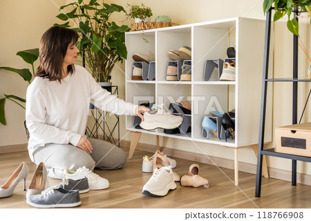 Smiling woman choosing footwear shoes closet comfortable storage contemporary organize at home Smiling woman choosing footwear shoes closet comfortable storage contemporary organize at home 118766908