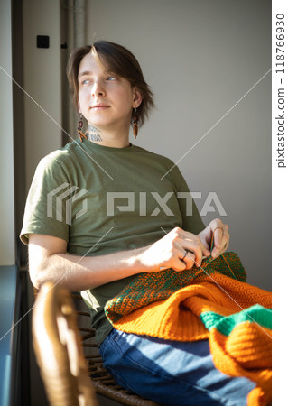 Feminine hipster man crochet handmade use hook knitting needles and wool yarn relaxing on couch 118766930