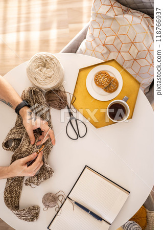 Feminine male hands crochet handmade artwork hobby wooden table with sewing tools closeup top view Feminine male hands crochet handmade artwork hobby wooden table with sewing tools closeup top view 118766937