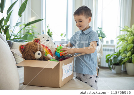 Boy child puts toys in a cardboard box for charity. Donation concept. Boy child puts toys in a cardboard box for charity. Donation concept. 118766956