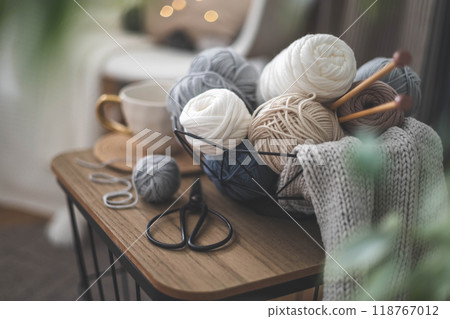 Cozy homely atmosphere. Female hobby knitting. Yarn in neutral colors in a white iron wire basket. 118767012