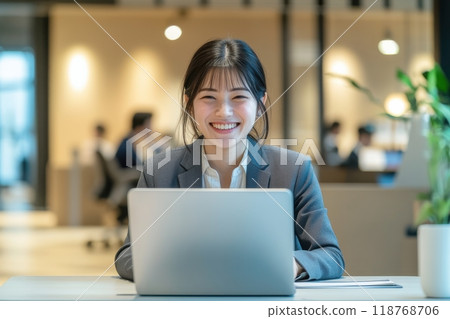 Smiling female office worker with laptop (free desk, remote work, coworking space) 118768706
