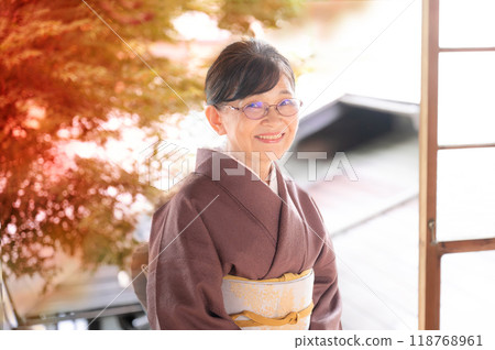 For autumn travel images, etc. A photo of a female innkeeper looking at the camera with autumn leaves in the background 118768961