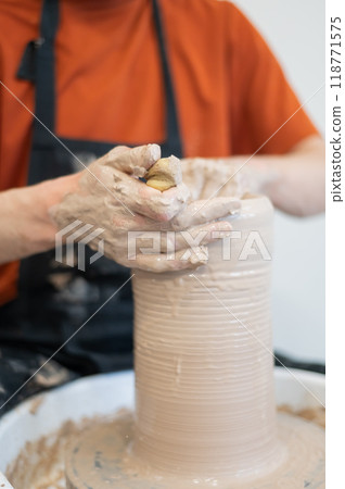 Close-up of a potter's hands making a ceramic vase on a potter's wheel. Vertical photo. Close-up of a potter's hands making a ceramic vase on a potter's wheel. Vertical photo. 118771575