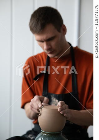 A potter works with a tool on a potter's wheel. A potter works with a tool on a potter's wheel. 118771576