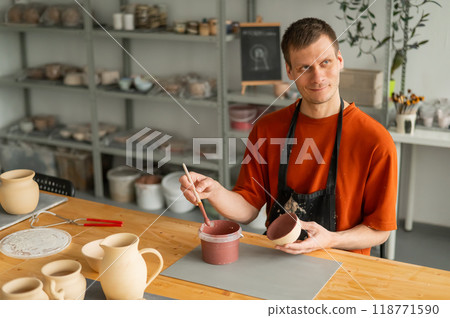Potter paints ceramic dishes with a brush. Potter paints ceramic dishes with a brush. 118771590