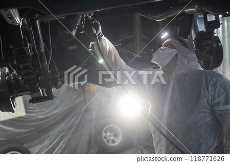 The master sprays an anti-corrosion compound on the bottom of the car. The master sprays an anti-corrosion compound on the bottom of the car. 118771626