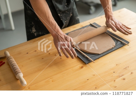 Close-up of potter's hands rolling out clay.  118771827