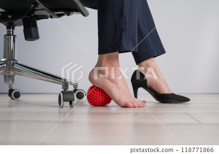 Business woman massages her feet on a massage ball with spikes. 118771866