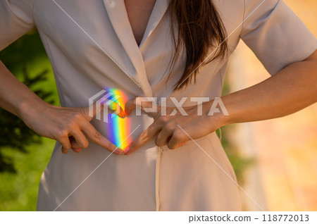 Faceless woman catching rainbow ray with her hands outdoors. Girl makes a heart with her hands Faceless woman catching rainbow ray with her hands outdoors. Girl makes a heart with her hands 118772013